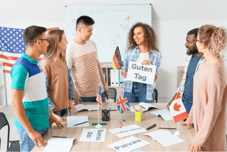 Un grupo de jóvenes sujetando distintas banderas, y carteles que tienen escrito "buenos días" en varios idiomas.
