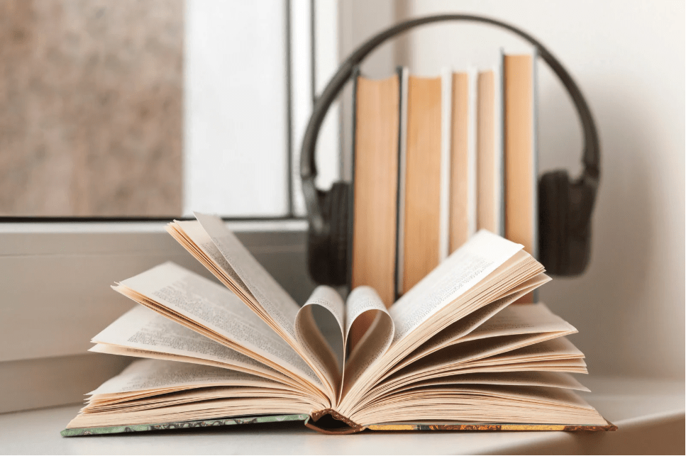 Un libro abierto de forma que sus hojas forman un corazón, y cascos sobre otro montón de libros.