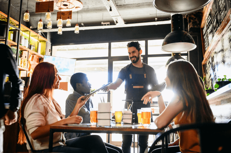 Un camarero tendiéndole un menú a una joven en un restaurante.