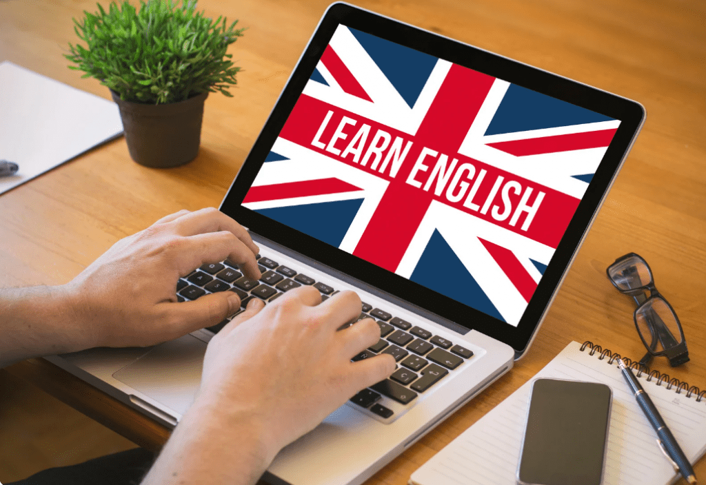 Unas manos sobre un portátil cuya pantalla reza "Learn English" sobre el fondo de una bandera inglesa.