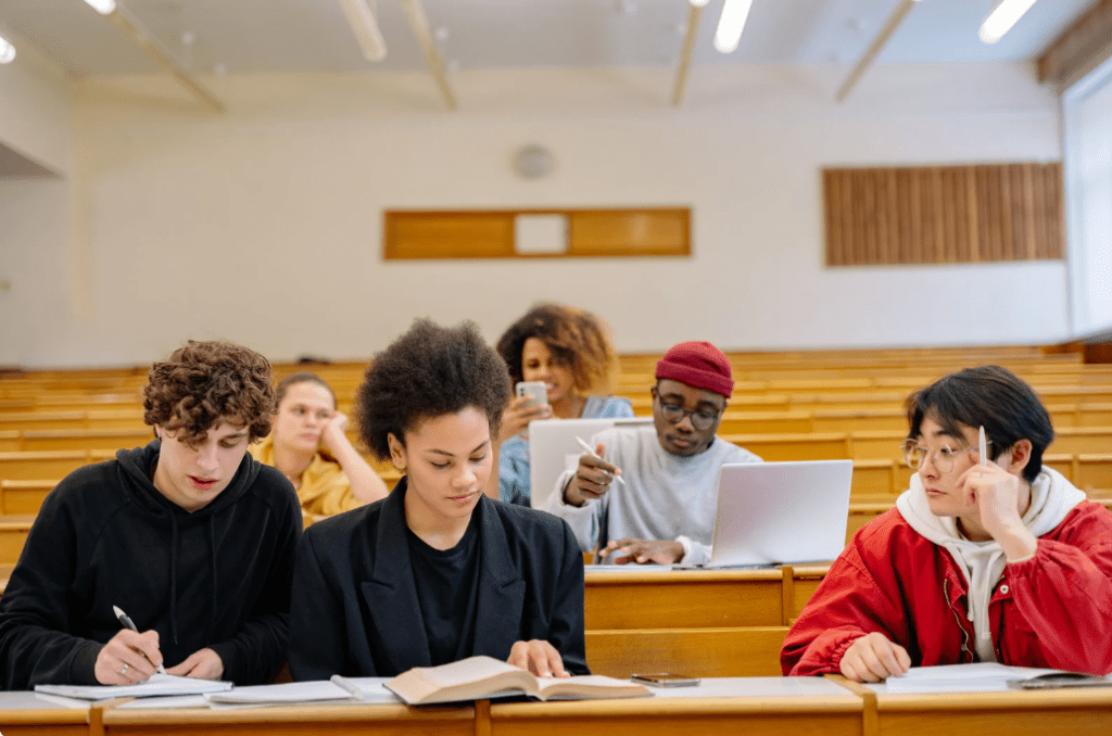 Una clase de universidad con varios jóvenes leyendo.