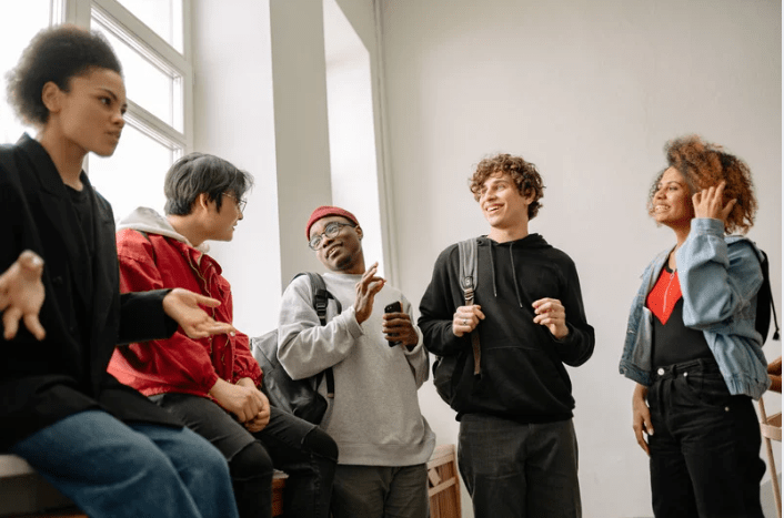 Un grupo de jóvenes charlando cerca de una gran ventana.