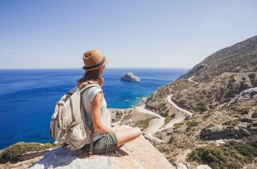 Una joven sobre una roca mirando el paisaje de acantilado marítimo.