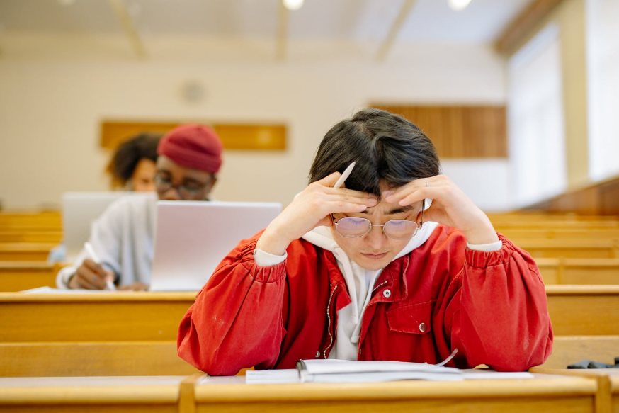 Un par de jóvenes concentrados sobre pupitres universitarios.