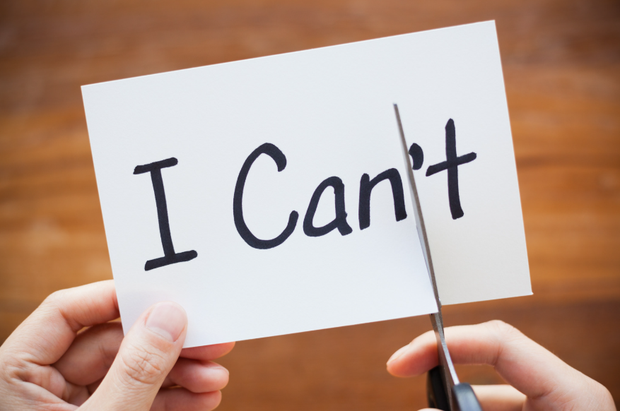 Un papel con las palabras escritas "I can't", y unas tijeras recortándolo para que en su lugar se lea "I can".